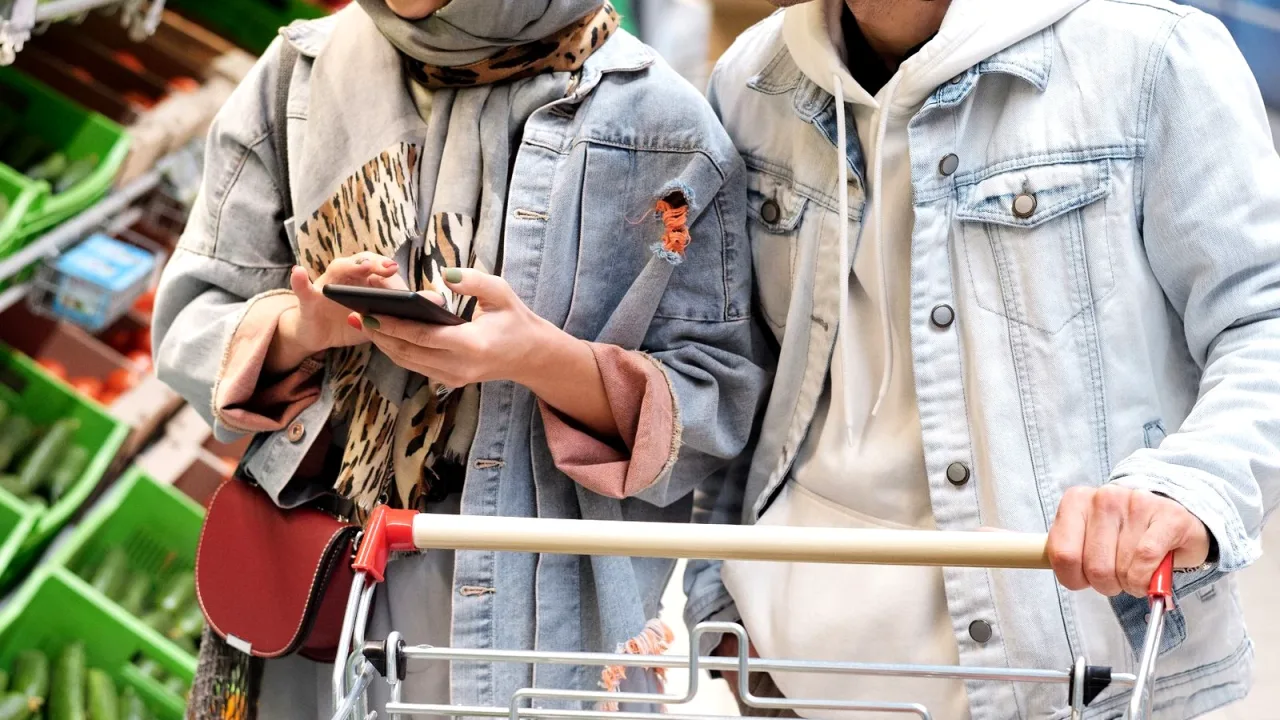 Markette dolu alışveriş arabasıyla alışveriş yapan iki kişi