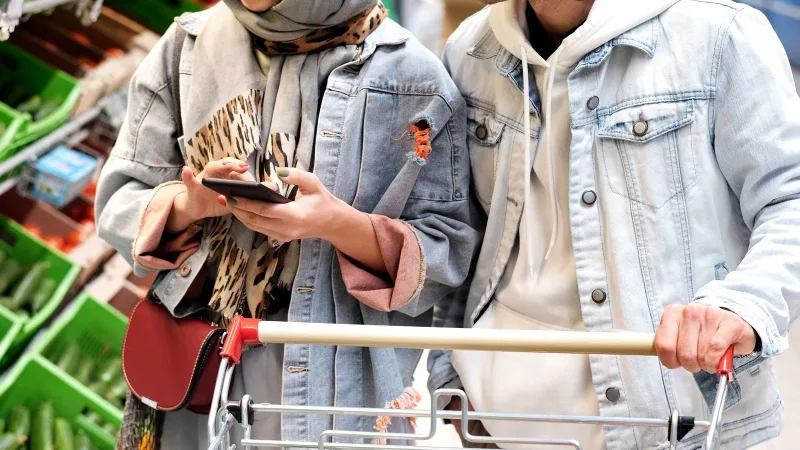 Markette dolu alışveriş arabasıyla alışveriş yapan iki kişi